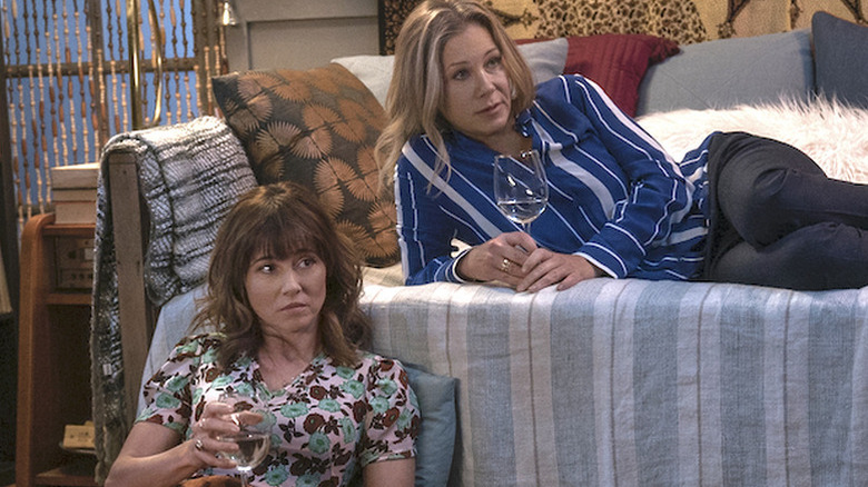 Linda Cardellini as Judy sitting on the floor with glass of wine next to Christina Applegate as Jen in Dead to Me