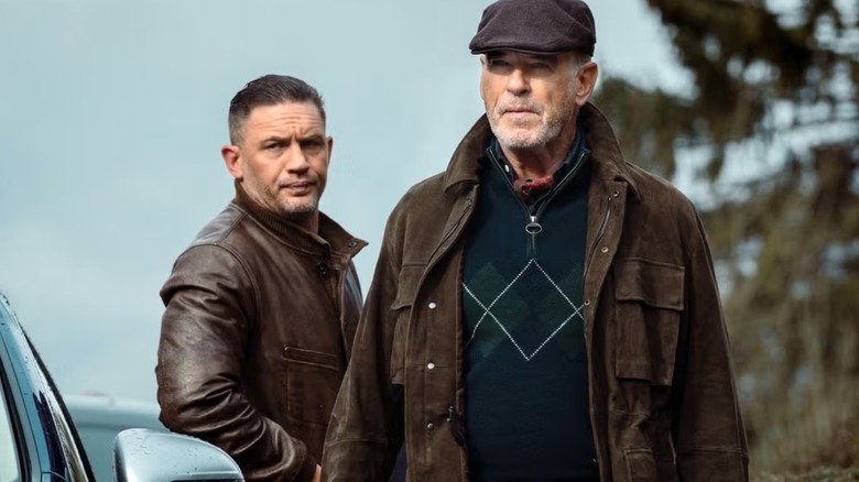 Harry (Tom Hardy) leans against a car behind Conrad (Pierce Brosnan) in MobLand