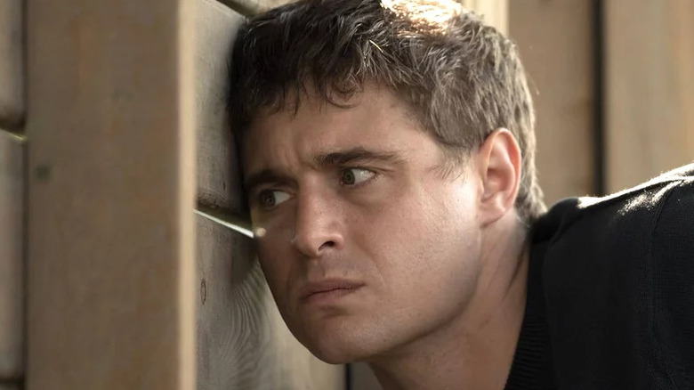 Max Irons' Joe Turner peeking through a slit in a wooden wall on Condor