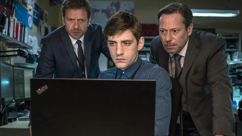 Jonathan Zaccaï's Raymond Sisteron, Jules Sagot's Sylvain Ellenstein, and Mathieu Amalric's Jean-Jacques Angel looking at a computer screen on the Bureau