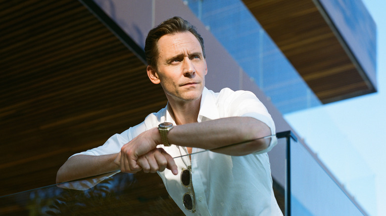 Tom Hiddleston's Jonathan Pine leaning on a glass bannister on The Night Manager