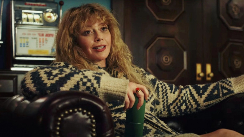 Natasha Lyonne sitting in chair wearing a sweater as Charlie in Poker Face