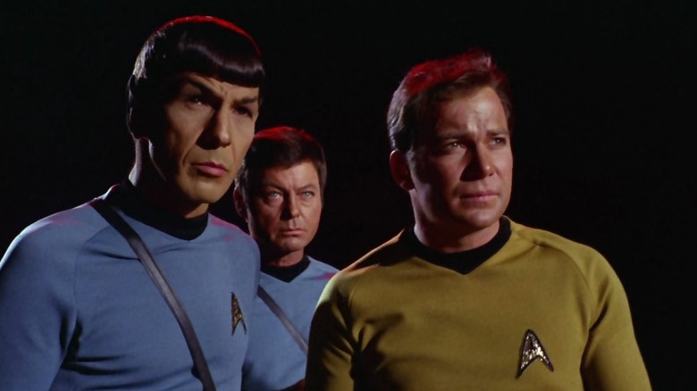 Spock, Dr. McCoy, and Captain Kirk standing warily in a dark environment on Star Trek S3E12