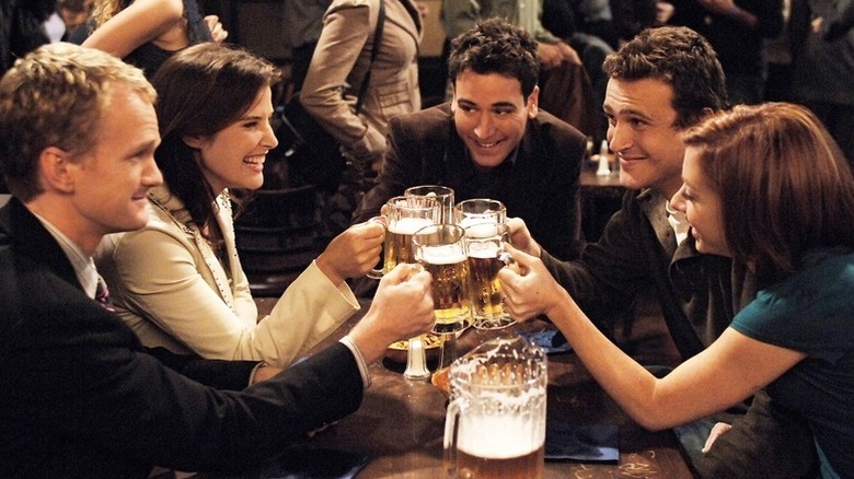 Barney, Robin, Ted, Marshall, and Lily cheers beer glasses in "How I Met Your Mother"