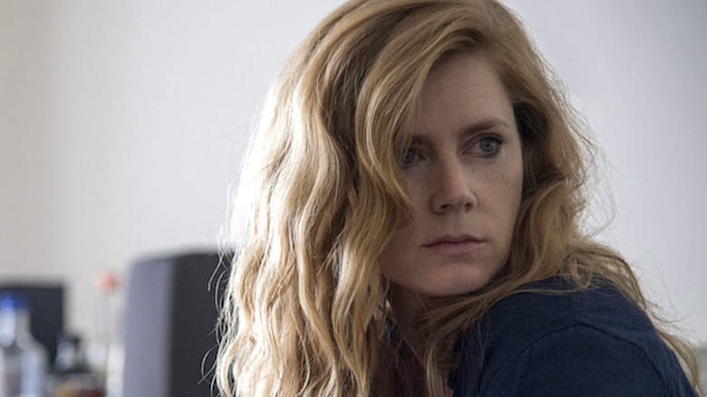 Camille sits on a bed in "Sharp Objects"