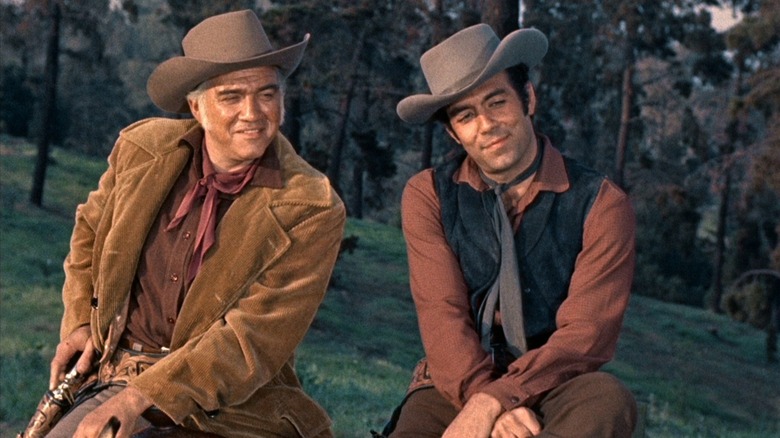 Lorne Greene as Ben Cartwright sits next to Pernell Roberts as Adam Cartwright on Bonanza