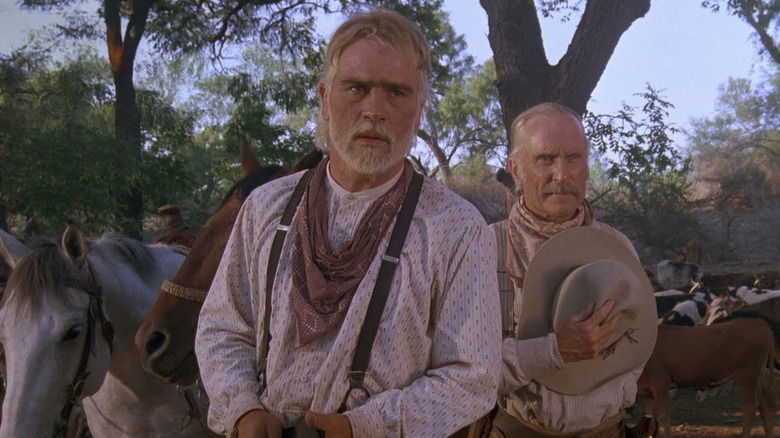 Tommy Lee Jones as Woodrow F. Call stands next to Robert Duvall as Augustus "Gus" McCrae in Lonesome Dove