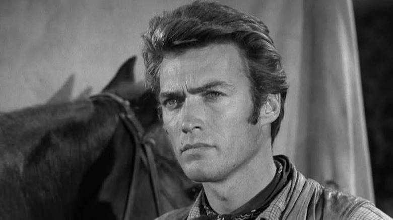 Clint Eastwood as Rowdy Yates stands in front of a horse in Rawhide