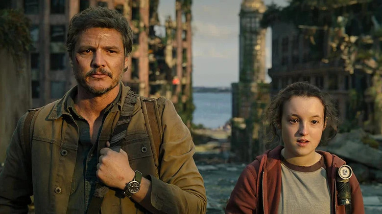 Joel Miller (Pedro Pascal) and Ellie (Bella Ramsey) stand next to each other in a ruined city in The Last of Us