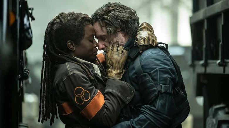 Michonne (Danai Gurira) and Rick Grimes (Andrew Lincoln) embrace between trucks in The Walking Dead: The Ones Who Live