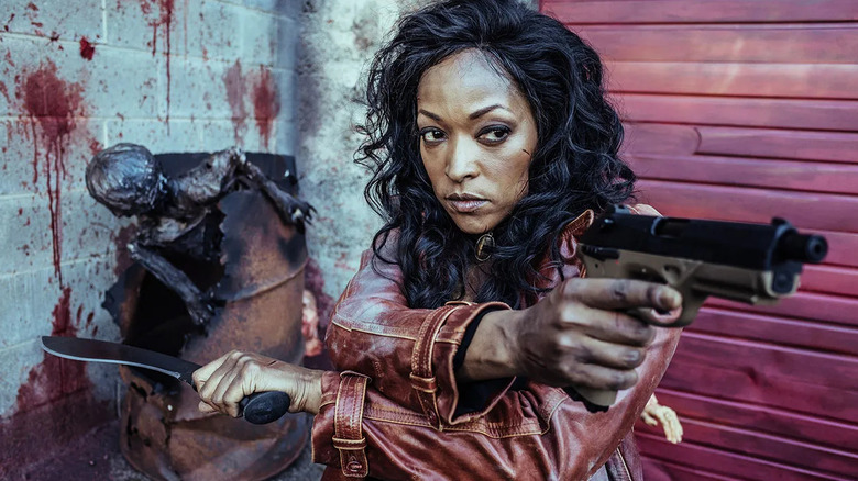 Roberta Warren (Kellita Smith) brandishes a pistol and a knife by a bloody wall in Z Nation