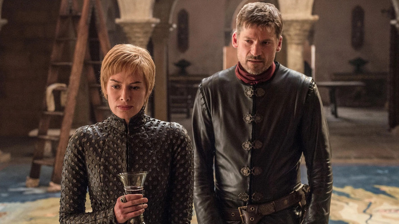 Lena Headey as Cersei holding a glass of wine with Nikolaj Coster-Waldau as Jaime standing behind her in Game of Thrones