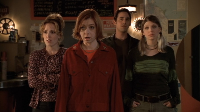 Emma Caulfied as Anya, Alyson Hannigan as Willow, Nicholas Brendon as Xander, and Amber Benson as Tara all looking shocked as they watch Giles sing in "Buffy the Vampire Slayer."