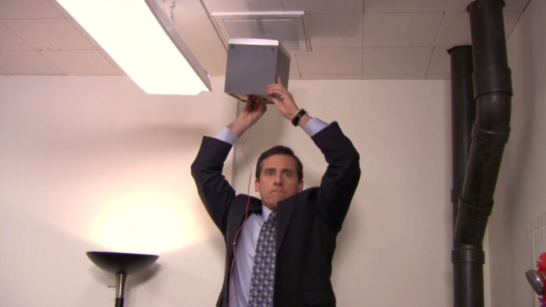 Steve Carell as Michael Scott holds up a speaker on The Office
