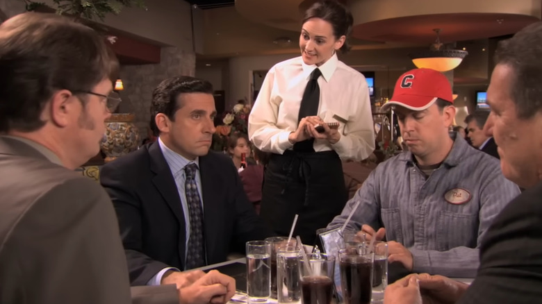 Steve Carell as Michael Scott talks to a waitress next to Ed Helms as Andy Bernard on The Office