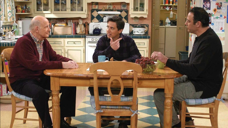 Peter Boyle as Frank Barone, Ray Romano as Ray Barone, and Brad Garrett as Robert Barone talk around a table on Everybody Loves Raymond