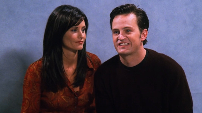Courteney Cox as Monica Geller acting frustrated with Matthew Perry as Chandler Bing while he is unable to smile normally for their engagement photo in Friends