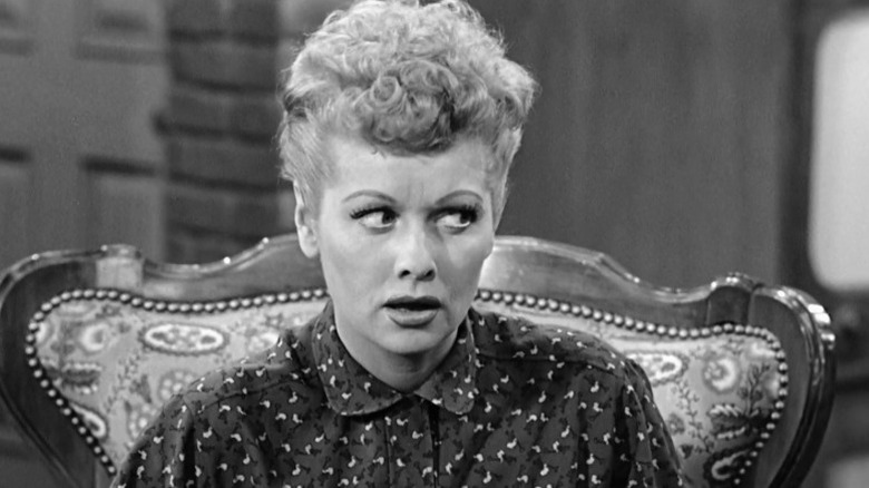 Lucy sitting and looking suspiciously to her left on I Love Lucy S1E30