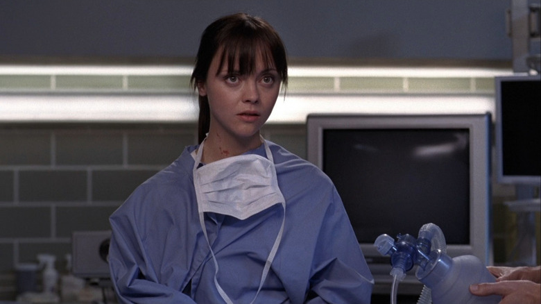 Hannah Davies in blue hospital scrubs looking worried
