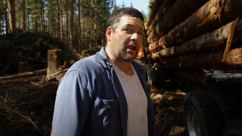 Todd Dewey standing in front of truck of logs on Ax Men