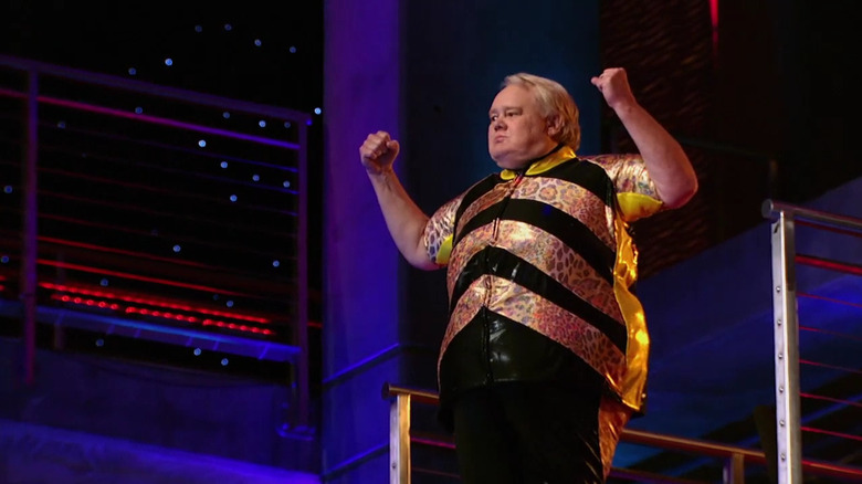 Louie Anderson in black and gold costume standing on diving platform in Splash