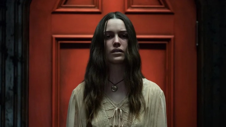 Nell Crain (Victoria Pedretti) in front of the Red Door in The Haunting of Hill House