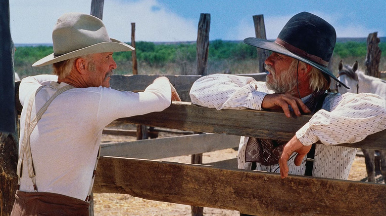 Robert Duvall as Augustus "Gus" McCrae and Tommy Lee Jones as Woodrow F. Call, looking at each other over a fence in Lonesome Dove.