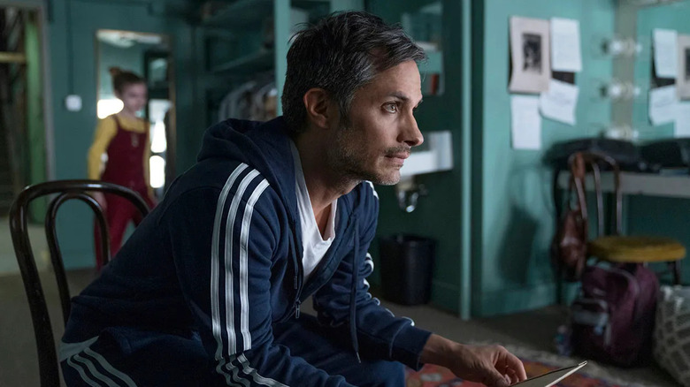 Gael García Bernal as Arthur Leander, leaning over a table in Station Eleven.
