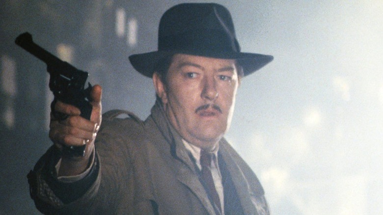Michael Gambon as Philip Marlow, dressed as a detective and aiming a gun in The Singing Detective.