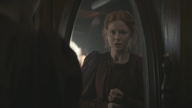 Emily Beecham's Maura looking at herself in the mirror in 1899