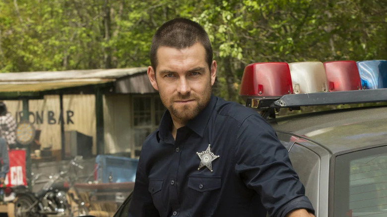Lucas Hood leaning on a cop car