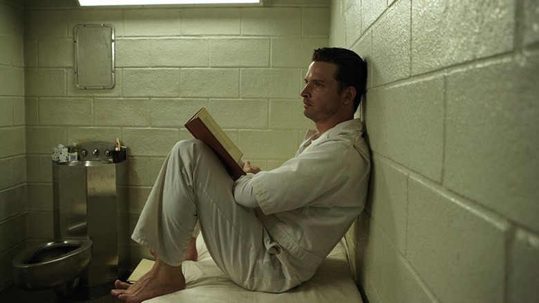 Daniel Holden reading a book in prison