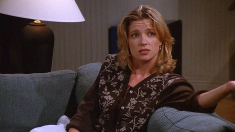 Donna Chang (Angela Dohrmann) sits inquisitively on a couch on Seinfeld