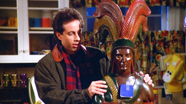 Jerry Seinfeld holds a large wooden Native American figure in Seinfeld