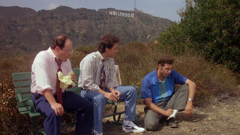 George Costanza (Jason Alexander) and Jerry Seinfeld sit on a park bench by Cosmo Kramer (Michael Richards) in front of the Hollywood sign on Seinfeld