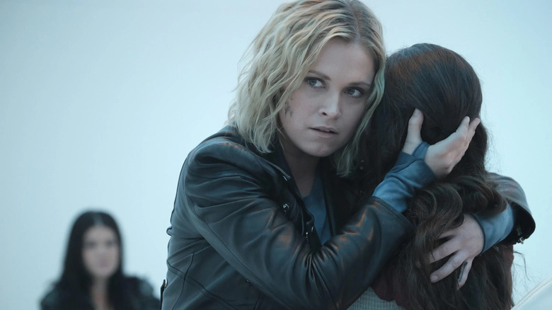 Eliza Taylor as Clarke holding a girl in The 100