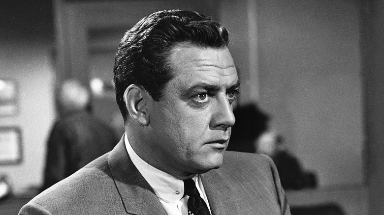 Raymond Burr as Perry Mason, sitting on a desk in Perry Mason.