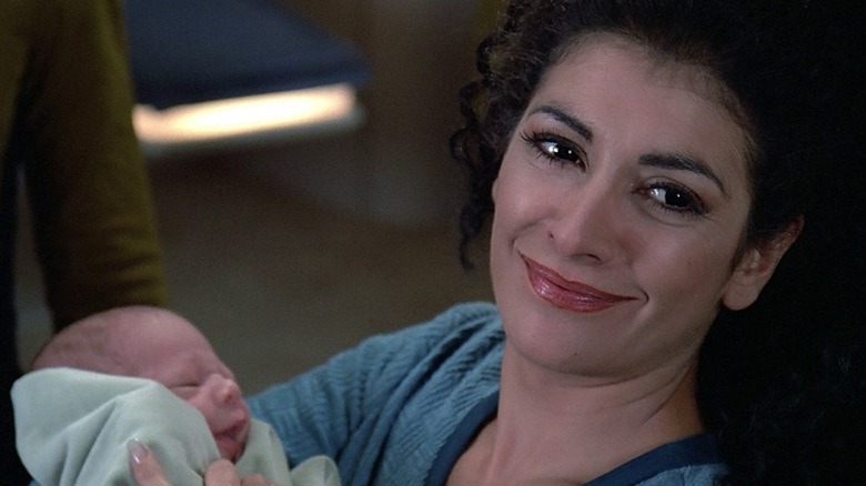 An emotional Deanna Troi (Marina Sirtis) smiles holding her baby on Star Trek: The Next Generation