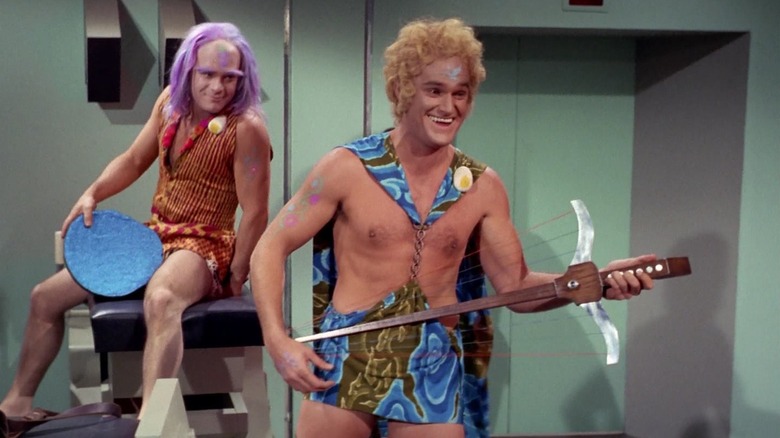 Adam (Charles Napier) happily plays an instrument while Tongo Rad (Victor Brandt) watches smiling on Star Trek: The Original Series