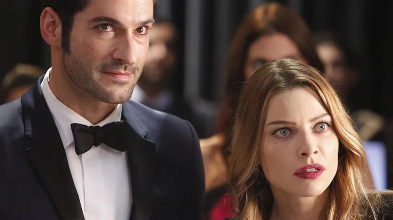 Tom Ellis as Lucifer stands next to Lauren German as Chloe Decker in Lucifer