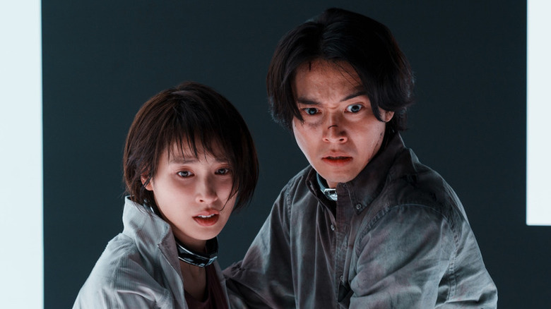 Yuzuha Usagi (Tao Tsuchiya) and Ryōhei Arisu (Kenta Yamazaki) hold each other in surprise on Alice in Borderland