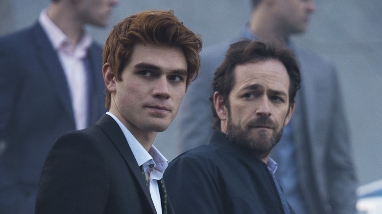 Archie Andrews (KJ Apa) and Fred Andrews (Luke Perry) stand somberly wearing suits in Riverdale