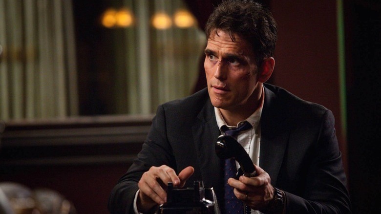 A battered Ethan Burke (Matt Dillon) puts his hand on a phone receiver in Wayward Pines