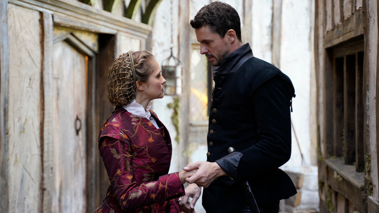 Diana Bishop (Teresa Palmer) and Matthew Clairmont (Matthew Goode) hold each others' hands while wearing Elizabethan English clothing in A Discovery of Witches