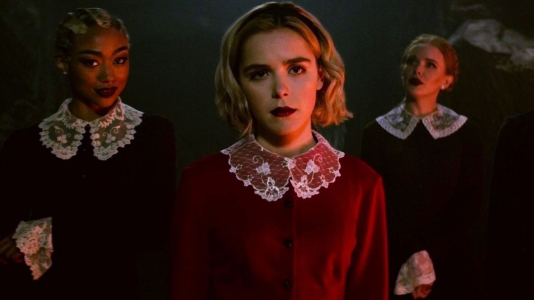 Sabrina Spellman (Kiernan Shipka) stands by a fire flanked by Prudence Blacwood (Tati Gabrielle) and Dorcas (Abigail Cowen) in Chilling Adventures of Sabrina