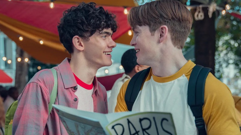 Charlie and Nick smiling at each other holding a map of Paris in Heartstopper