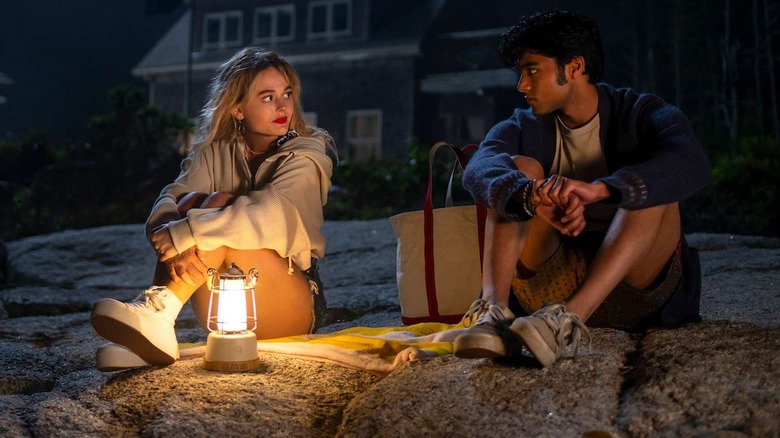 Cady and Gat sitting on the beach at night with a lantern looking at each other on We Were Liars