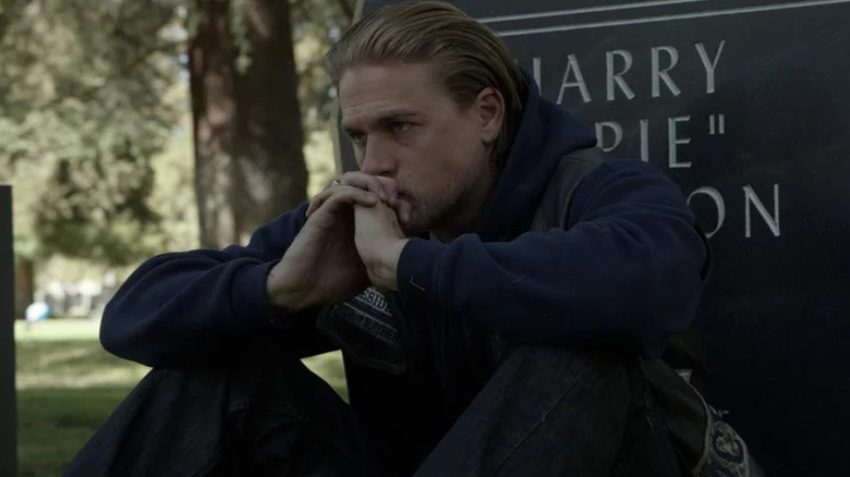 Charlie Hunnam's Jax Teller sitting by a gravestone on Sons of Anarchy
