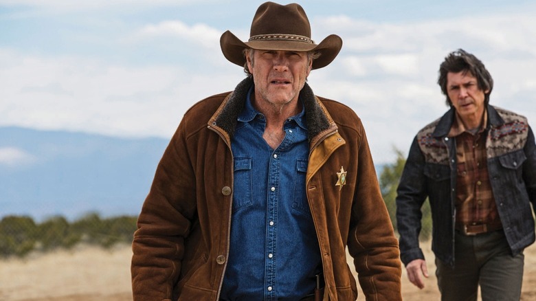 Walt Longmire (Robert Taylor) stares in the horizon while approached by Henry Standing Bear (Lou Diamond Phillips) in Longmire