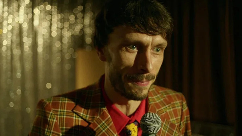 Donny in red plaid suit holding microphone in Baby Reindeer